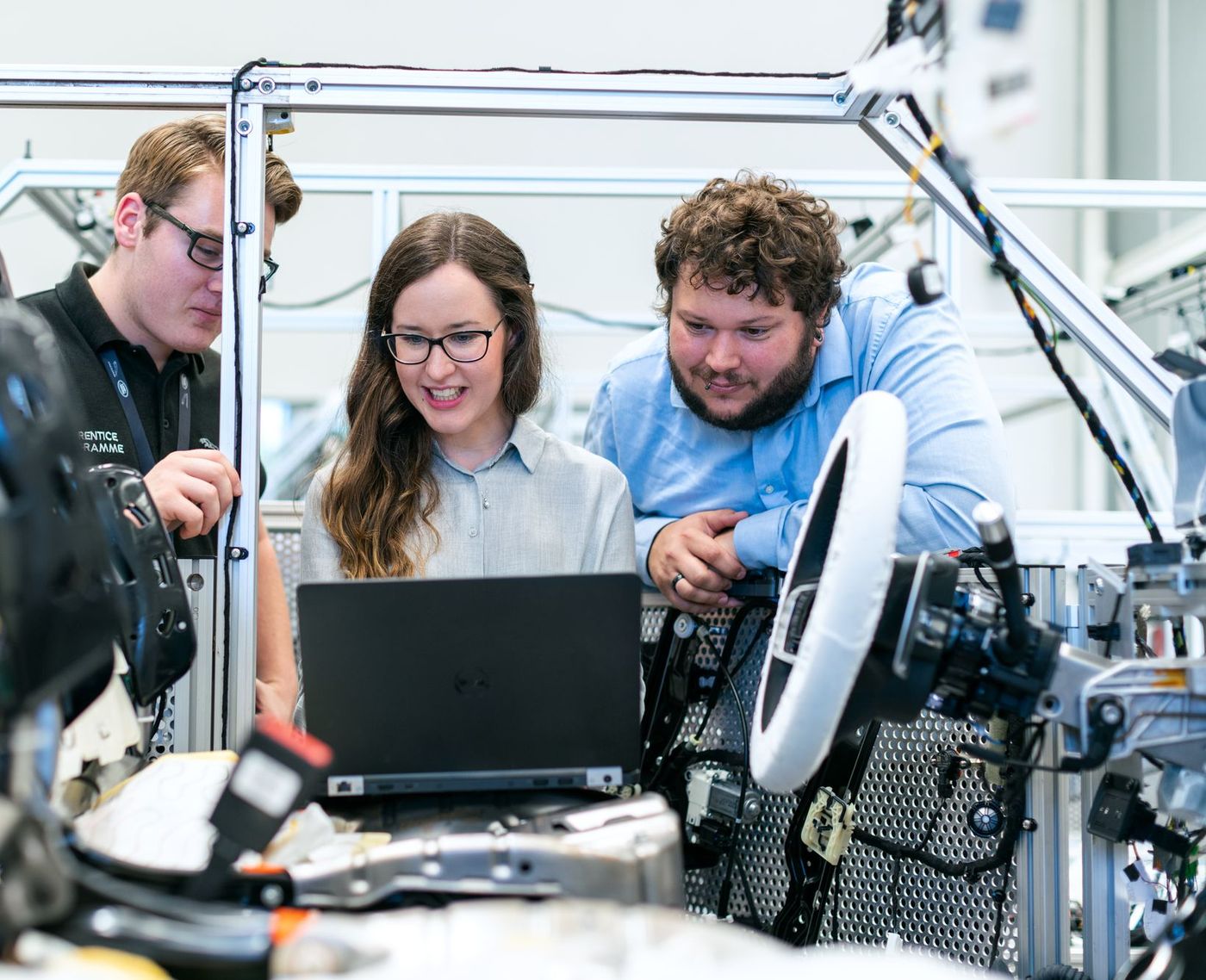 Three engineers studying a laptop readout inside an automotive test rig